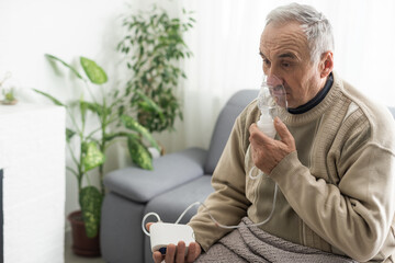 Sick elderly man makes inhalation.