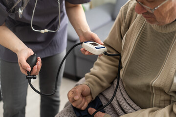 Nurse measure high blood pressure of a sick senior mature male patient in medical clinic closeup....