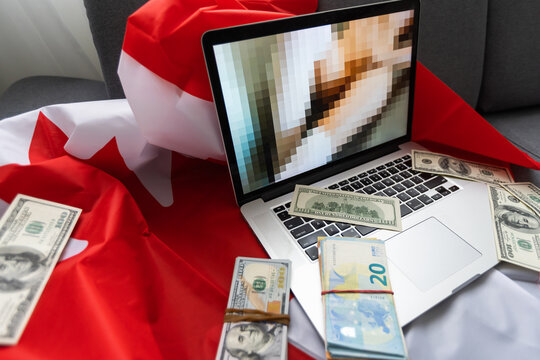 laptop with blurred screen, money and Canadian flag