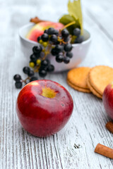 Red apples and grapes in  the bowl on white wooden background