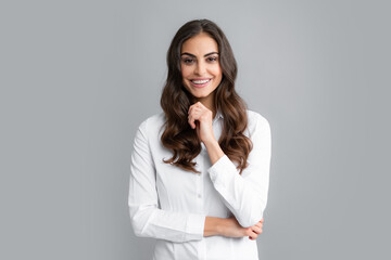 Pretty woman dressed casually in shirt looking with satisfaction. Studio shot of beautiful woman isolated against gray background.