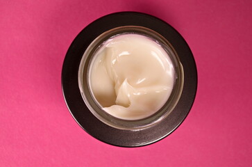 face cream in jar. close up. women's care concept. container with anti wrinkles cream on pink background