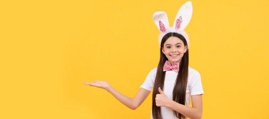 child girl in bunny ears and bow tie presenting product or shopping sales. Easter child horizontal poster. Web banner header of bunny kid, copy space.