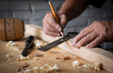 Carpenter cutting wood on wooden table in carpentry shop.