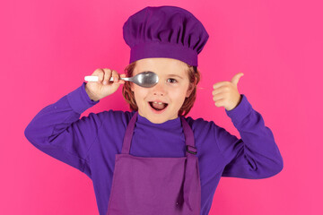 Child cook hold spoon. Excited chef cook. Child wearing cooker uniform and chef hat preparing food, studio portrait.