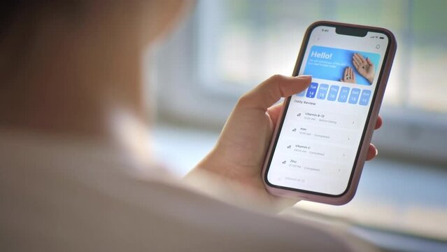 Close view of a person holding smartphone with opened medication tracker app