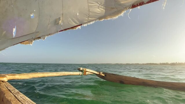 4K authentic wooden sailing fishing boat heading for open seas with rugged sail. Traveling, fishing lifestyle, tropical environment, indigenous peoples and remote places concept. Zanzibar, Tanzania.