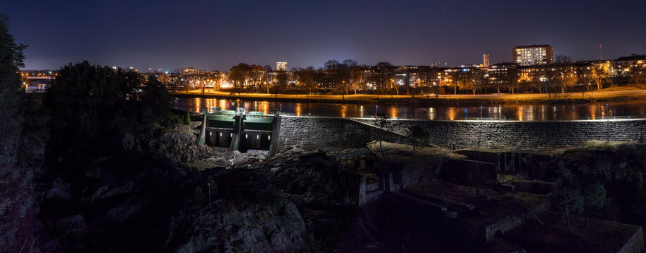 Gota Alv river and its old dam construction with glowing streetlights in Trollhattan City at nighttime. Taken with long exposure capturing the impressive construction of this historical site.