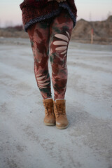 Woman legs in handmade cut out leggings, outdoors on a dirty road