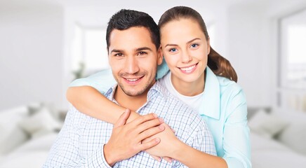 Smiling young couple hugging in the living room.