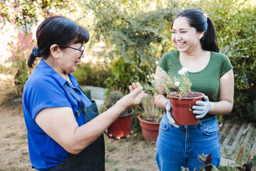 Fototapeta premium Family of gardeners in her organic garden. They are holding a flower pot with plants