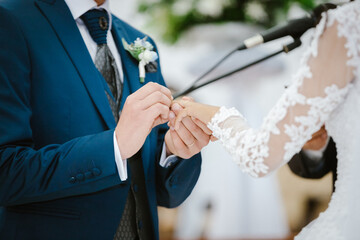 Novio pone anillo a su novia en su boda