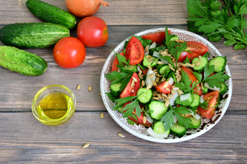 A bowl of cucumber salad with a bottle of olive oil and vegetables 