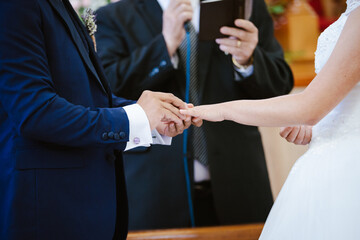 Novio pone anillo a su novia en su boda