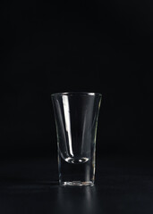 Vertical shot of Empty Glass of vodka on black background. An empty Drink Transparent Glass on a black background. Isolate. Copy space