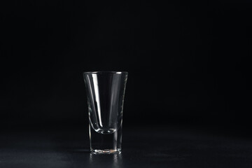 Empty Glass of vodka on black background. An empty Drink Transparent Glass on a black background. Isolate. Copy space
