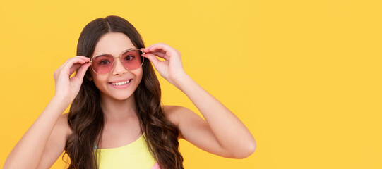 happy teen girl in summer glasses has curly hair on yellow background, summer fashion. Child face, horizontal poster, teenager girl isolated portrait, banner with copy space.