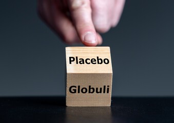 Symbol that homeopathic medicine has an placebo effect only. Hand turns cube and changes the German word 'Glubuli' (globule) to 'placebo'.