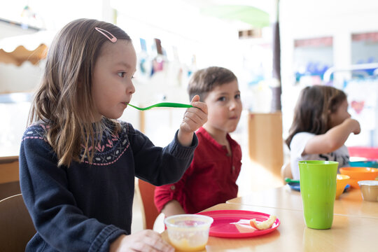 Preschool teacher and students eating during snack time in classroom