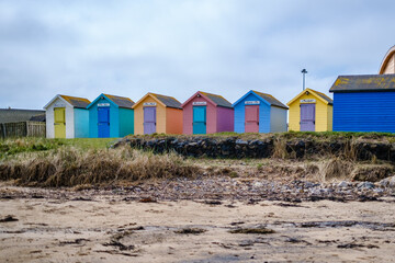 Fototapeta na wymiar Beach huts on the beach at Amble Marina on the Northumberland coast, England, UK