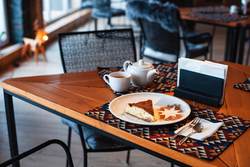 Chocolate cake on a white plate standing at wooden table