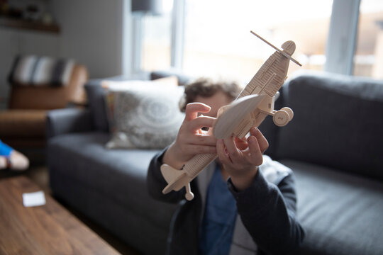 Boy playing, flying model airplane in living room