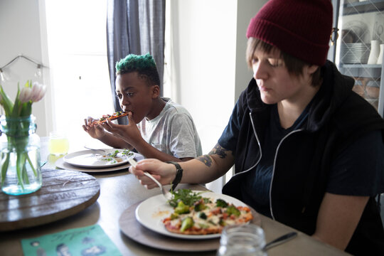 Homosexual Couple And Children Eating At Dining Table