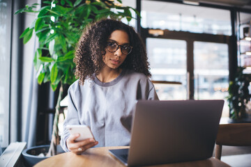 Focused ethnic woman using smartphone in cafe