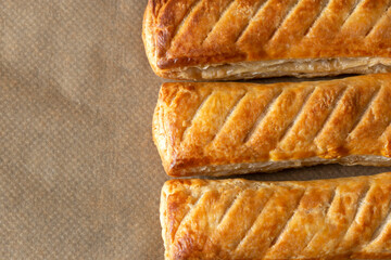 Sausage rolls cooked on brown greaseproof baking paper. Traditional British food concept.