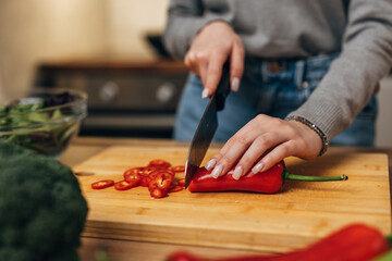 Closeup view of hands slicing red peeper with a kitchen knife