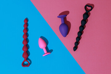 Top view of buttplugs and dildos for anal sex on colored background with shadows. Sex shop concept