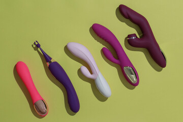 A lot of different dildo vibrators on yellow background with shadows. Sex toy for adult