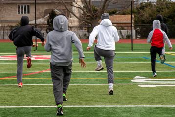 Runners on turf field performing running sports drills in winter