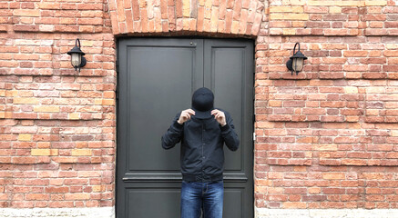Obraz na płótnie Canvas Young man standing near the front door of a brick house