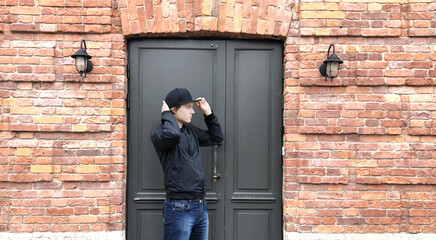 Young man standing near the front door of a brick house