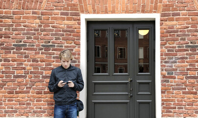 Young man standing near the front door of a brick house