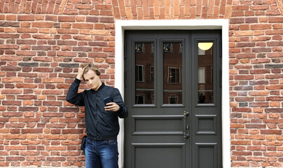 Young man standing near the front door of a brick house