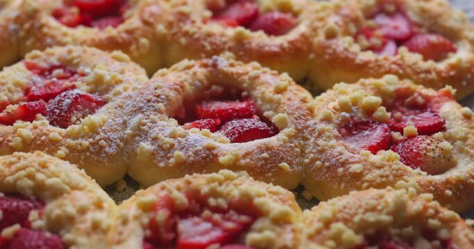 Sweet yeast buns with strawberries sprinkled with powdered sugar, close-up view