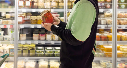Young man shopping in supermarket, reading product information.