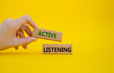 Active listening symbol. Wooden blocks with words Active listening. Businessman hand. Beautiful yellow background. Business and Active listening concept. Copy space.