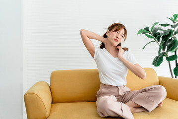Asian woman, attractive and young sitting on a sofa, is currently having a nape injury, to people...