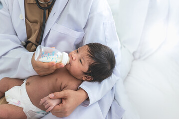 Woman gynecologist doctor feeding milk from bottle milk to 1-month-old baby newborn girl, to health...