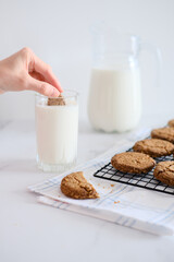 Woman's hand dipping homemade cookies into a glass of milk