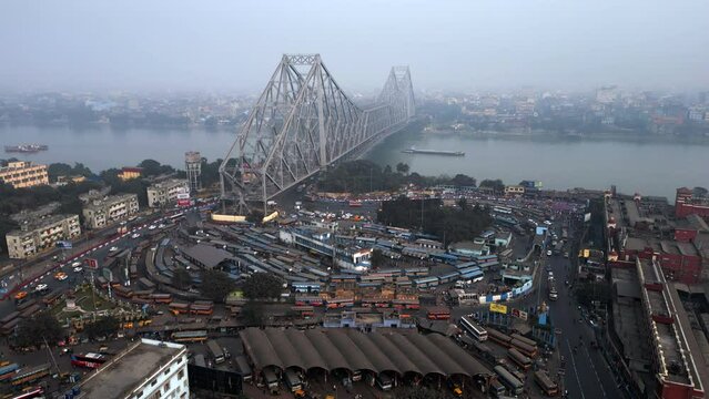 Aerial static shot showing architectural landmark Howrah Bridge over the Hooghly River on a smoggy day in Kolkata, India, one of the most polluted cities in the world.