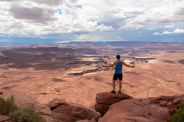 Fototapeta premium Man with scenic view of Split Mountain Canyon seen from Green River Overlook, Moab, Canyonlands National Park, San Juan County, Utah, USA. Looking at features of The Maze district and White Rim Road