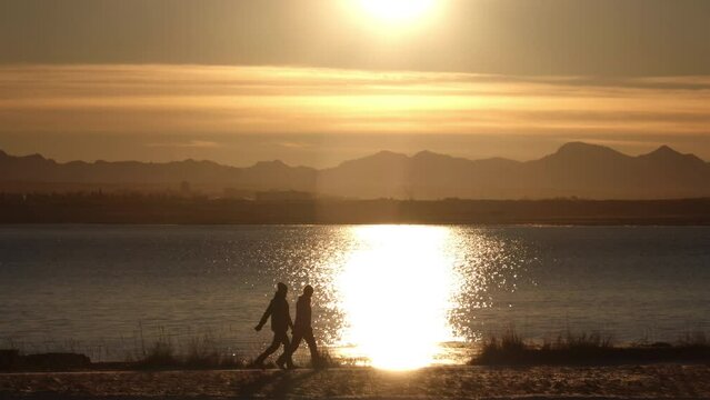 A couple walking by ocean sun reflection Reykjavik Iceland