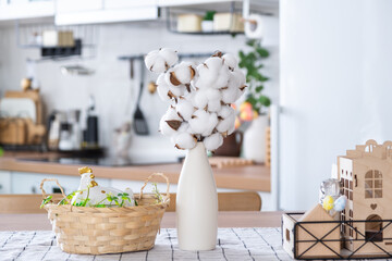Easter decoration of colorful eggs in a basket and a chicken on the kitchen table in a rustic style. Festive interior of a country house