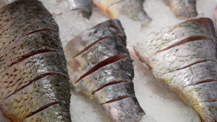 Fresh raw salmon, sturgeon, dorado fish and sea bass lie on the counter with ice in the fish market. Open shelf in a seafood store. Close-up.