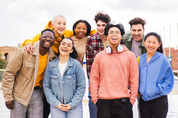Portrait of big group of teenage multiracial young friends smiling and looking at camera. Front view of a lot of happy school students laughing and having fun together standing outdoors. Friendship