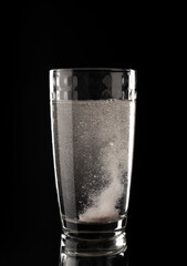 Effervescent pills. Glass with liquid in bubbles on a black background. Aspirin. Tablet of vitamins